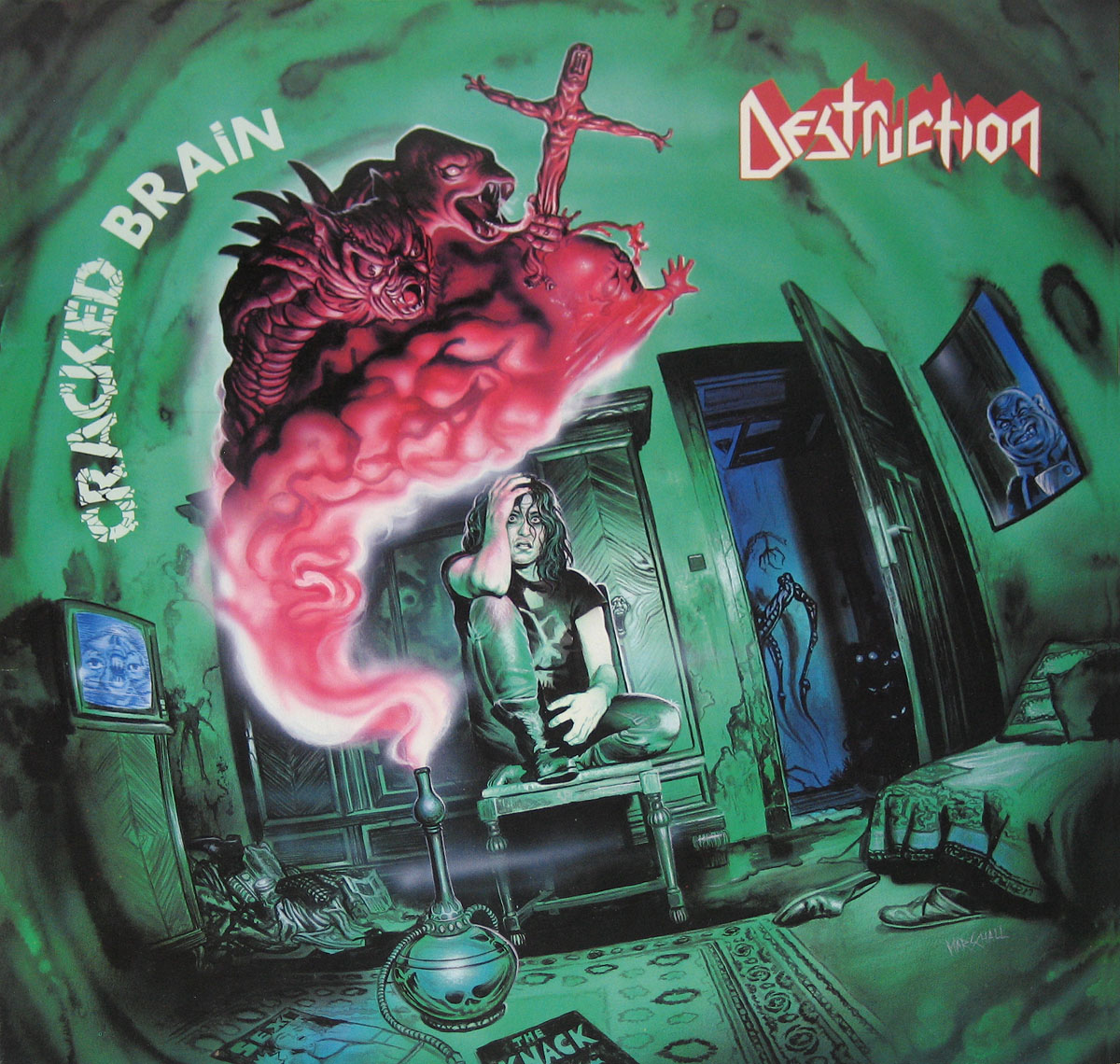 Album cover for Destruction’s “Cracked Brain,” featuring a surreal green-hued room with a distressed figure sitting on a piece of furniture, clutching their head. A red, smoke-like entity with demonic faces emerges from a skull-shaped contraption. The chaotic scene includes a glowing TV screen, shadowy figures, and eerie details, evoking themes of madness and horror.